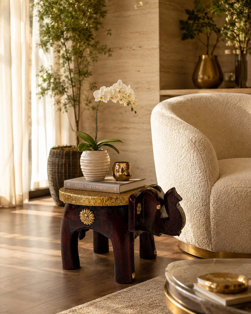 Elephant-shaped decorative accent stand styled beside an armchair