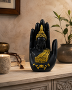 Black and gold Buddha sculpture in a blessing palm, styled on a console