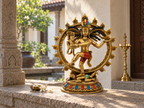 Gold-tone Nataraj Shiva idol displayed on a stone ledge in a sunlit courtyard