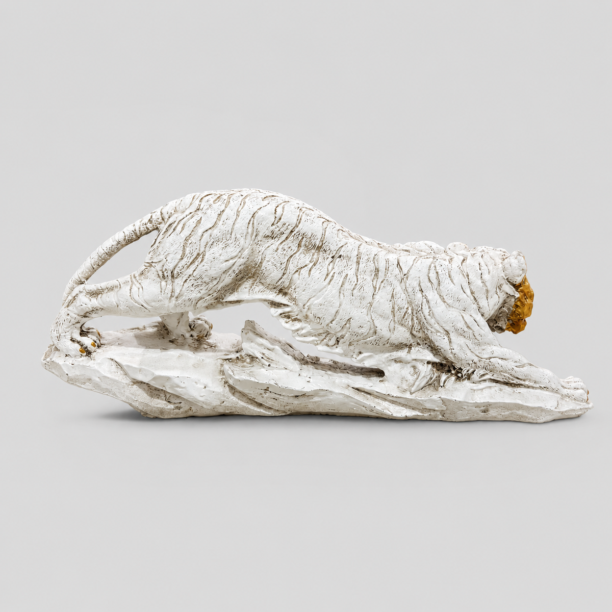 Ivory and gold crouching tiger sculpture on a rocky base, rear profile