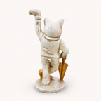 Dapper ivory and gold cat sculpture holding an umbrella, rear view