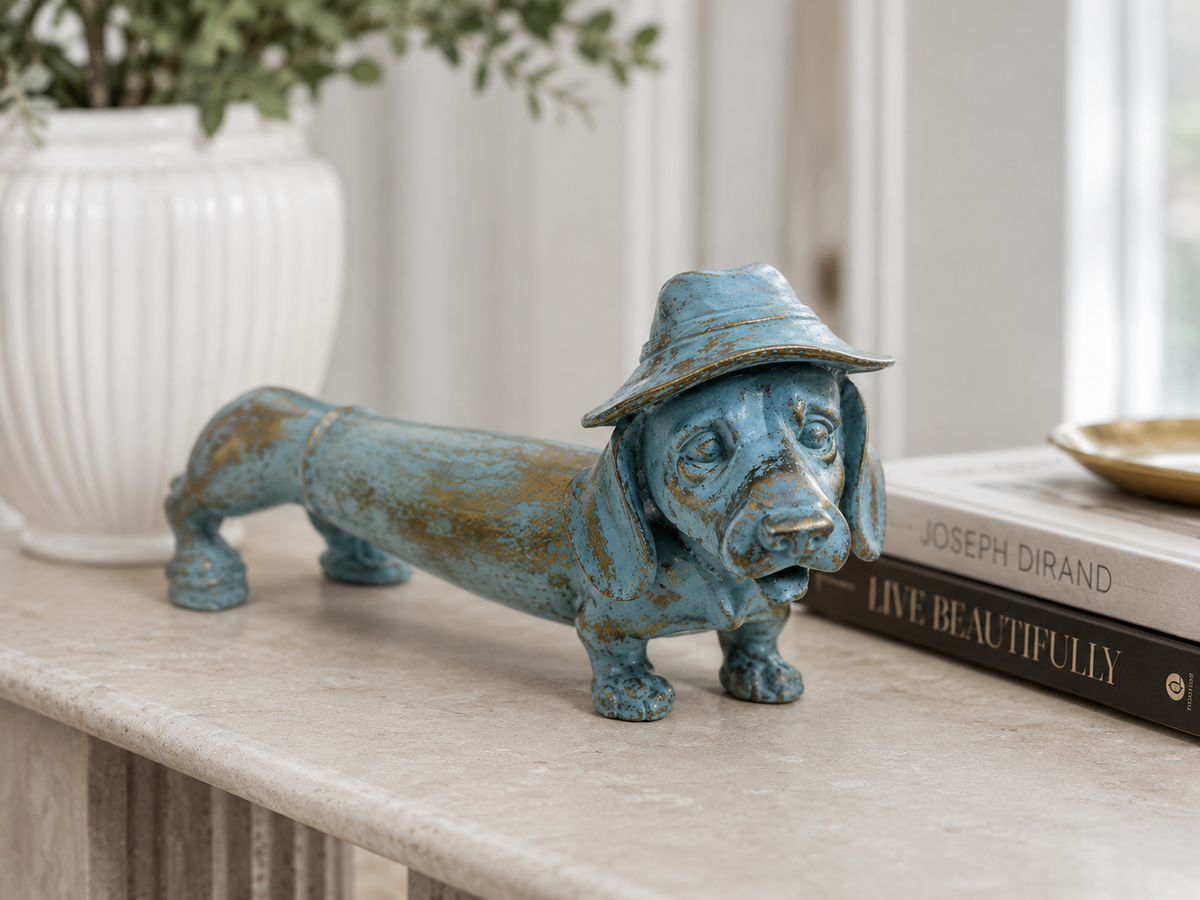 Blue and gold dachshund sculpture styled on a console beside books