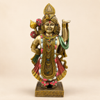Shrinathji idol standing with one arm raised, ornate gold-tone jewellery, a red garment and green drape, front view