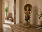 Standing Vishnu idol with Sheshnag displayed on a wooden console in a sunlit interior