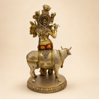 Rear view of the Krishna and cow idol showing the decorated headdress, flowing hair, patterned cow adornment and round base