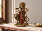 Durga idol with lion on a cloth-covered home altar beside white flowers