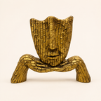 Golden mosaic face sculpture on a curved base, front view