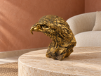Golden Sentinel eagle bust displayed on a stone coffee table in a warm living room
