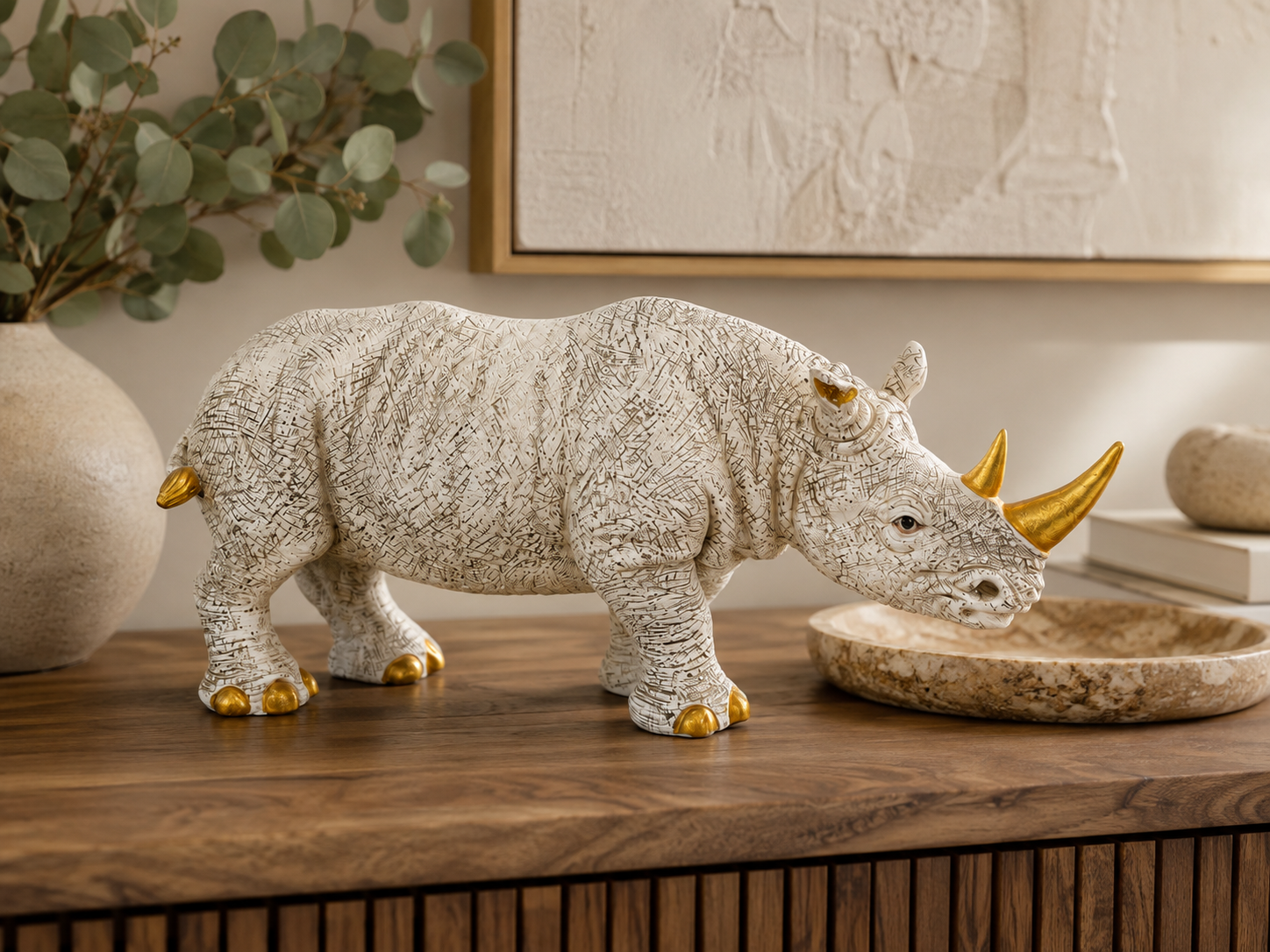 Ivory and gold rhino sculpture styled on a wooden console