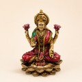 Lakshmi idol seated on a layered lotus with pink lotus flowers, a raised blessing hand, coins and red and green accents, front view