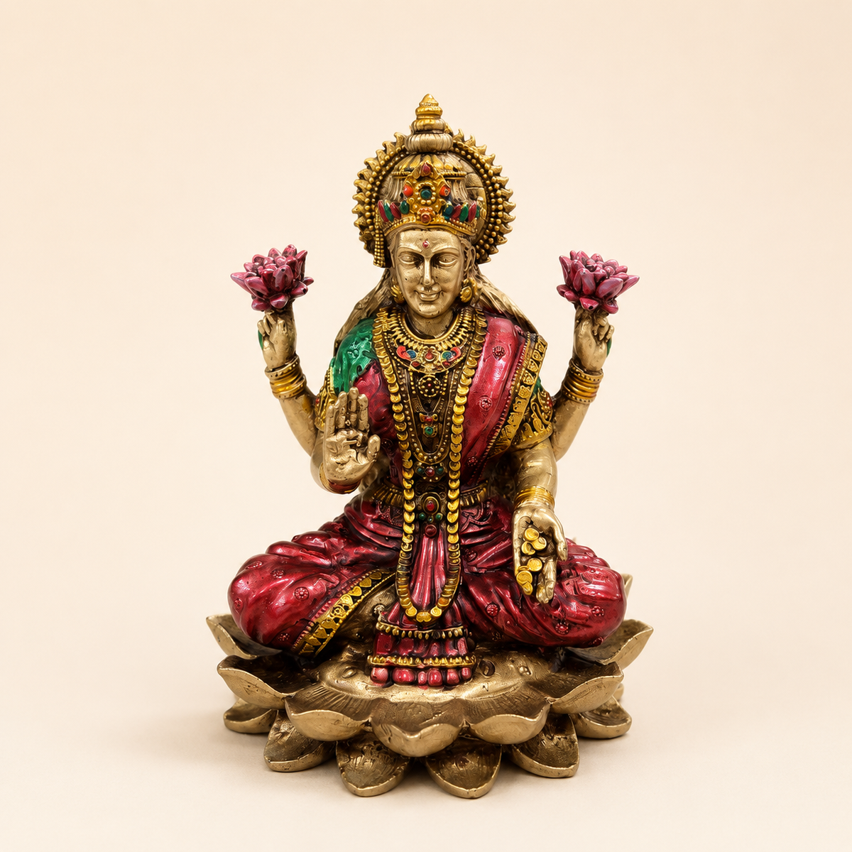 Lakshmi idol seated on a layered lotus with pink lotus flowers, a raised blessing hand, coins and red and green accents, front view