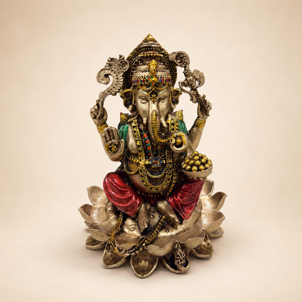 Ganesha idol seated on a layered lotus with a raised blessing hand, bowl of sweets, gold-tone finish and red and green accents, front view