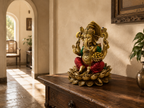 Ganesha idol displayed on a carved wooden console in a sunlit room