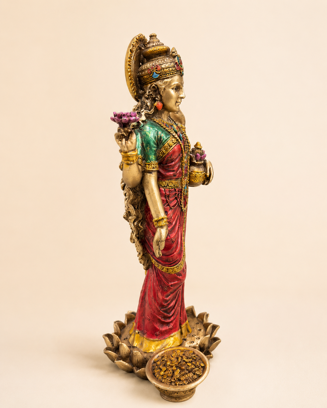 Angled view of the Lakshmi idol showing red and green attire, crown and lotus-style base