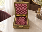 Open Mayur Bagh antique gold tone box with rose coloured lining styled on a dressing table