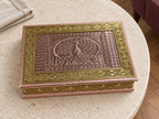 Detailed peacock and geometric lid patterns on the Mayur Darbar jewellery box displayed on a cream stone table