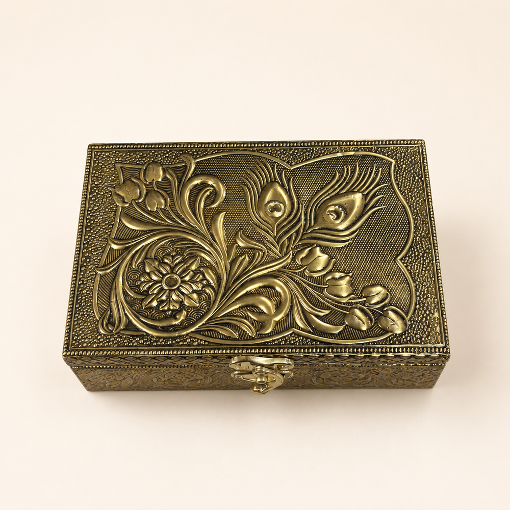 Top view of the Mor Pankh box showing raised peacock feathers, scrolling leaves and a floral medallion