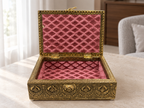 Open Mor Pankh antique gold tone jewellery box with rose coloured lining in a softly lit room