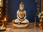 Meditating Hanuman idol in a shrine with a blue backdrop and glowing lamps