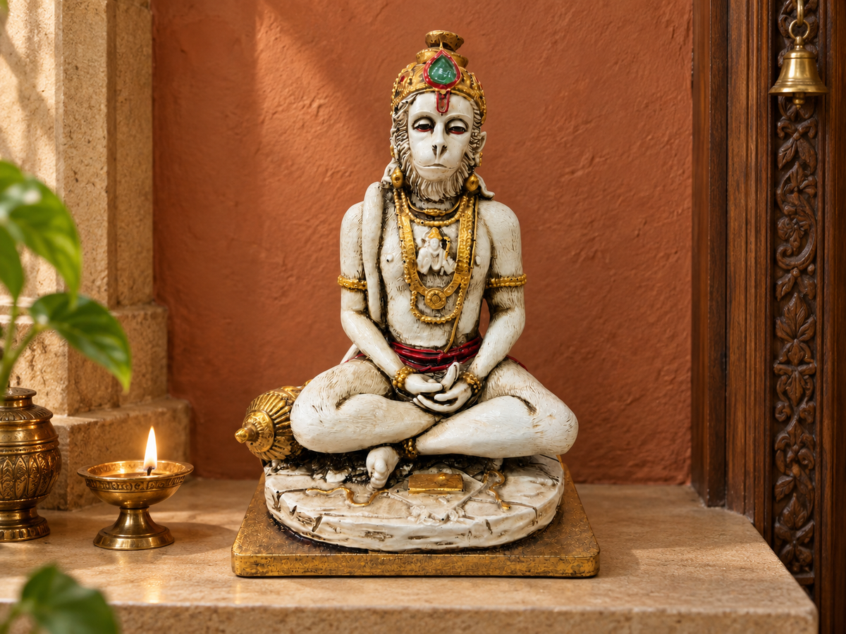 Ivory-tone and gold-tone meditating Hanuman idol on a sandstone altar