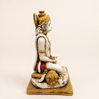 Side view of the seated Hanuman idol showing the crown, curled tail and gold-tone gada