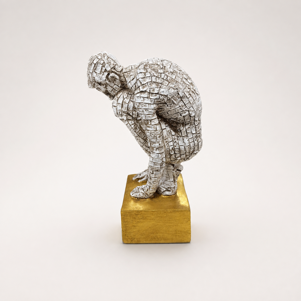 Silver-toned crouching mosaic figure sculpture on a gold base, front view