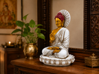 White, gold and red Buddha statue displayed on a wooden console