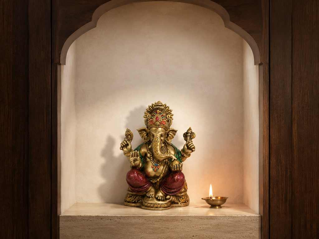 Ganesha idol displayed in a simple arched prayer niche beside a glowing diya