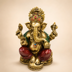 Seated Ganesha idol with ornate crown, gold-tone finish, red dhoti and green shawl, front view