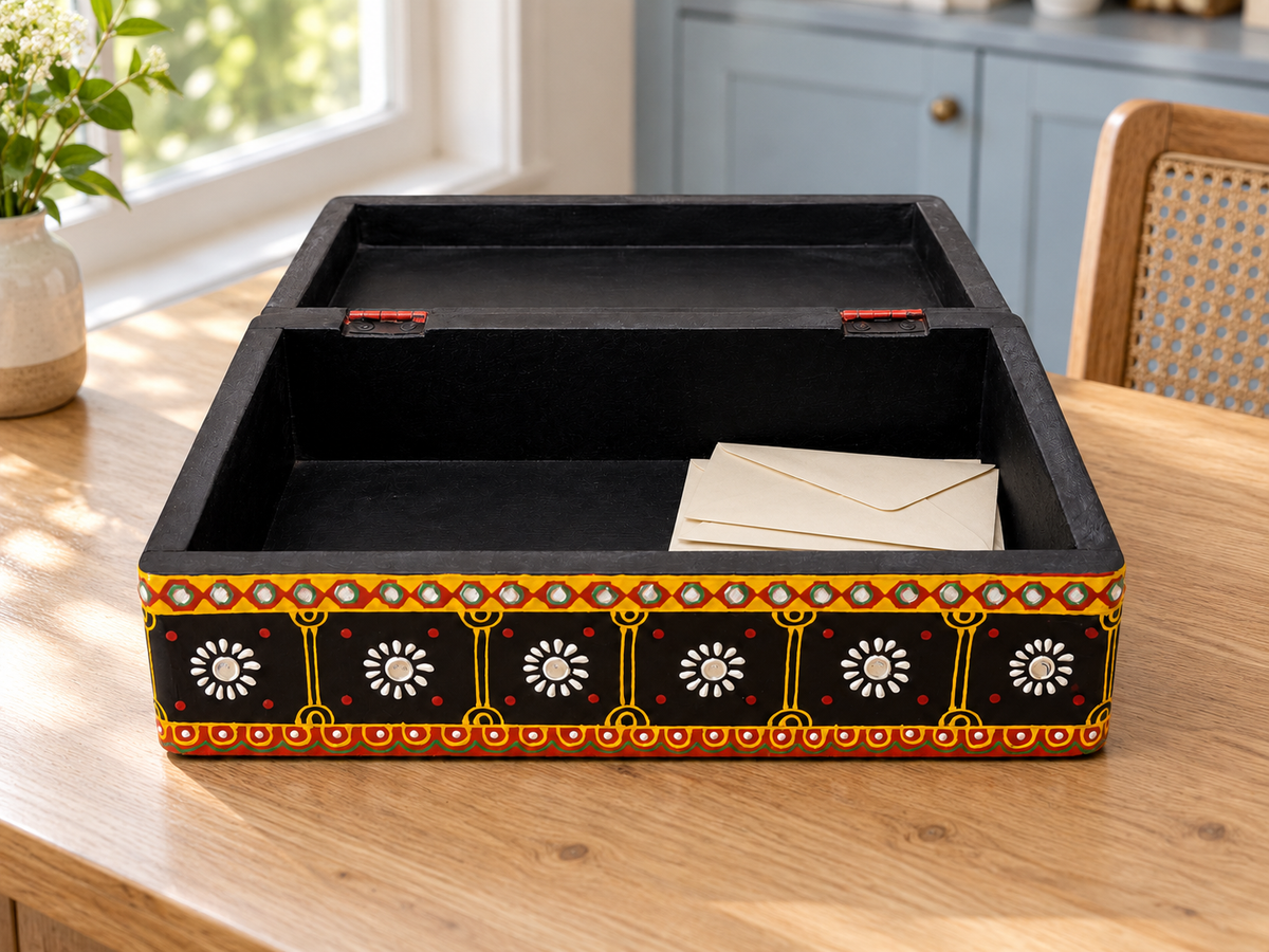Open Rang Jyoti keepsake box on a wooden table by a window, styled with ivory envelopes