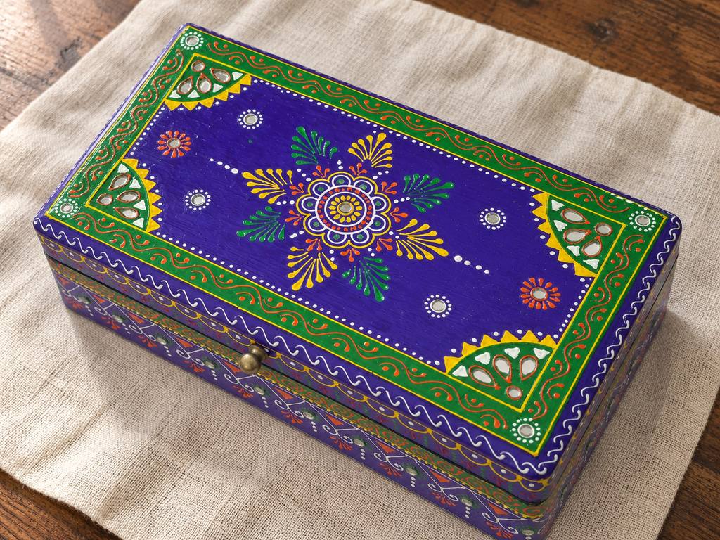 Overhead view of Rang Leela keepsake box on a linen runner showing floral decoration and mirror accents