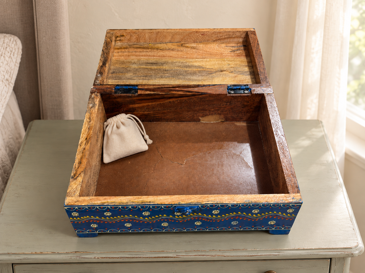 Open Rang Tarang blue floral chest styled with a small ivory coloured pouch on a light table