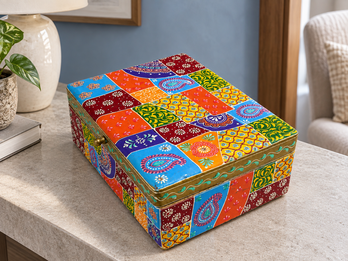 Angled view of the Rangoli Patchwork storage box on a stone side table beside a lamp and books