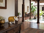 Ivory and gold raised-trunk elephant sculpture displayed on a dark wood table beside a traditional courtyard