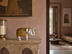 Ivory and gold raised-trunk elephant sculpture styled on a stone console in a warm pink interior