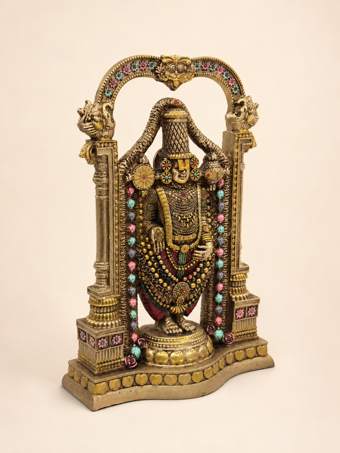 Angled view of the Tirupati Balaji idol showing the floral arch, decorated pillars and pedestal