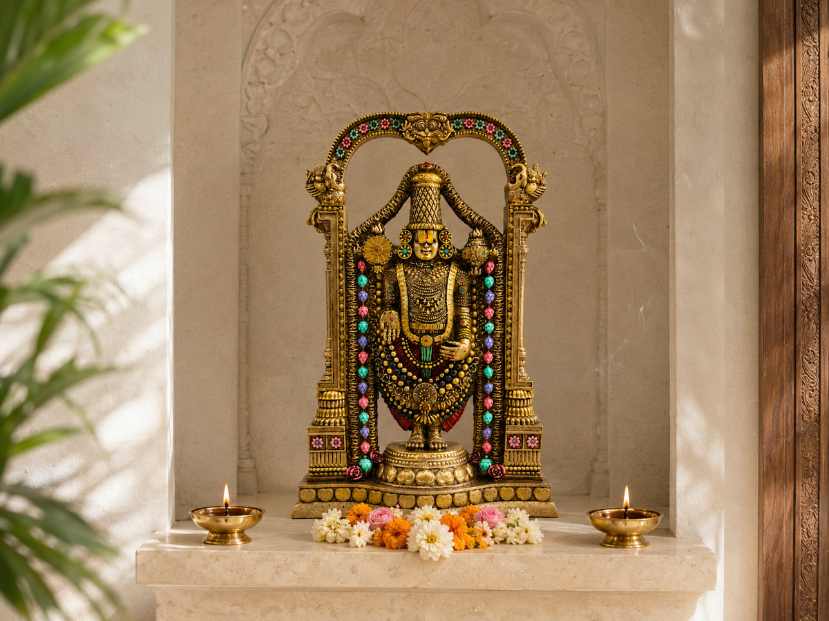 Tirupati Balaji idol in a light prayer niche with two diyas and a floral offering