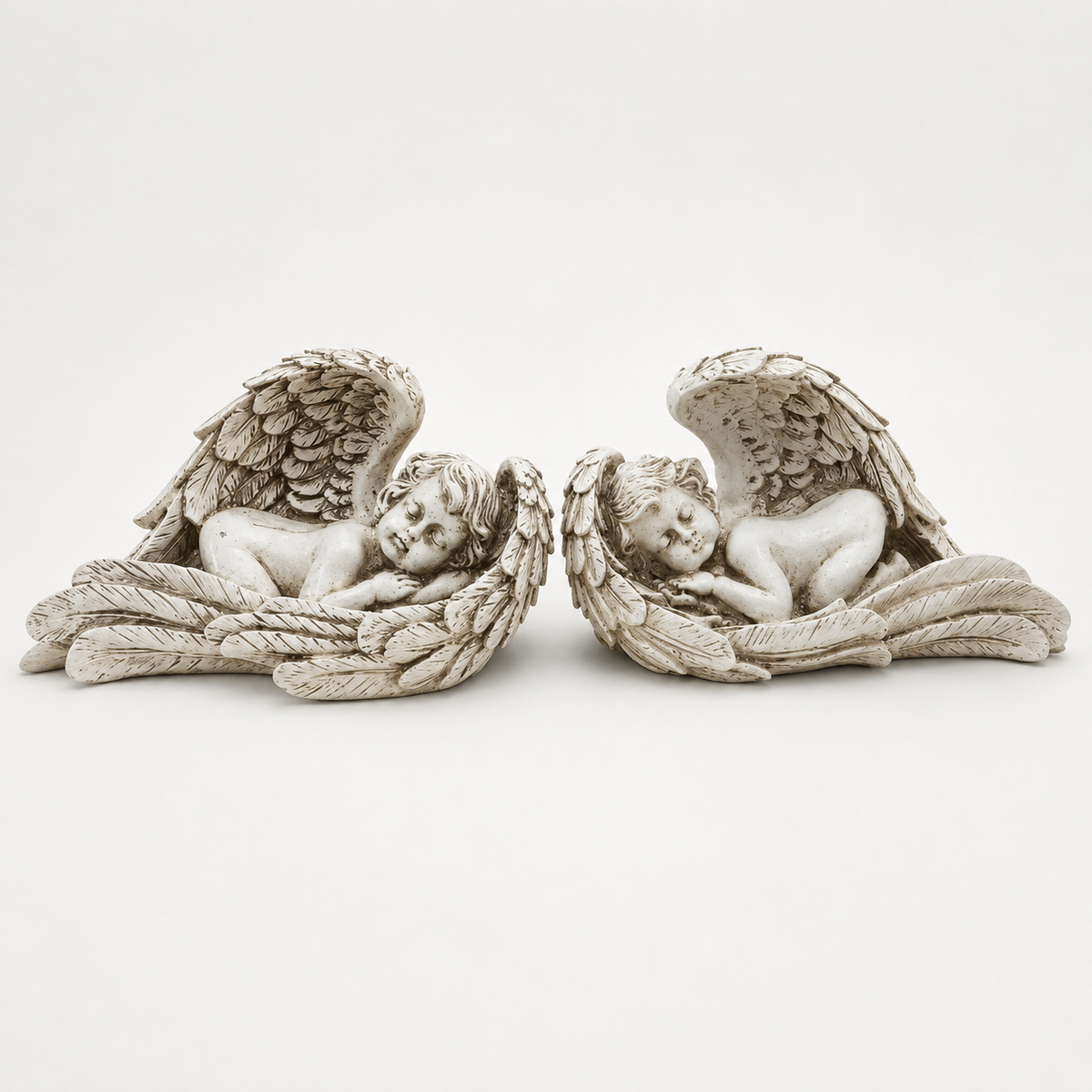 Pair of antique ivory sleeping angel wing sculptures, front view