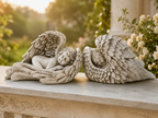 Pair of sleeping angel wing sculptures styled on an outdoor stone ledge
