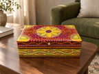 Surya Mandala red and yellow keepsake box on a wooden table beside a green sofa