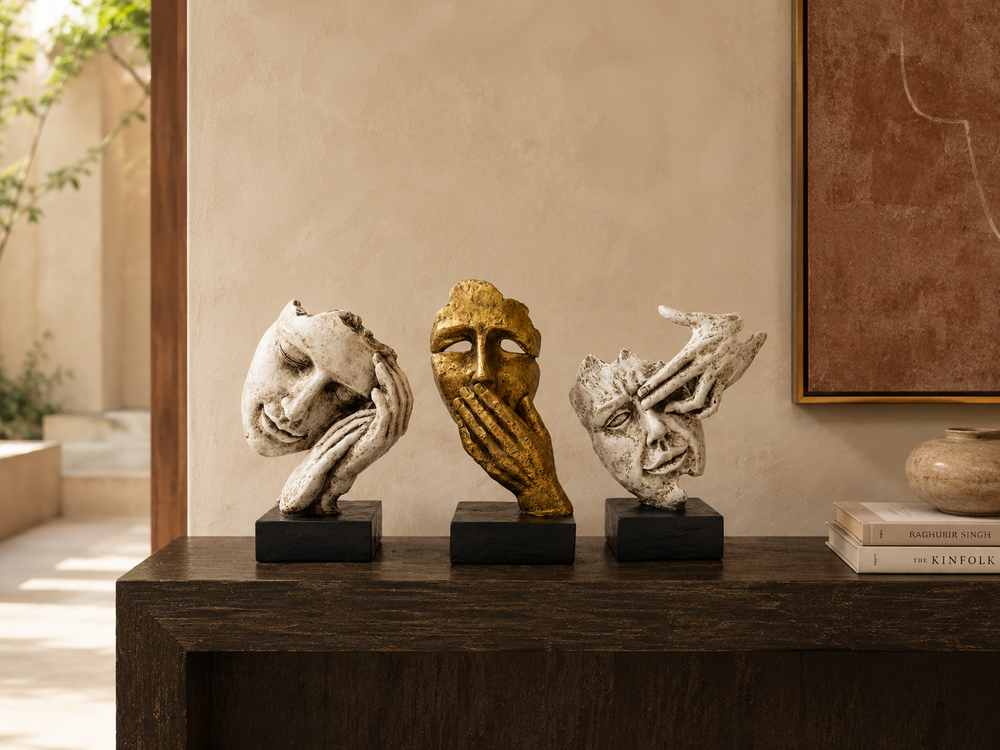 Ivory and gold expressive face sculpture trio displayed on a dark wood console