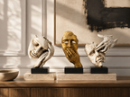 Unspoken Stories face sculpture trio styled on pale plinths above a wood credenza