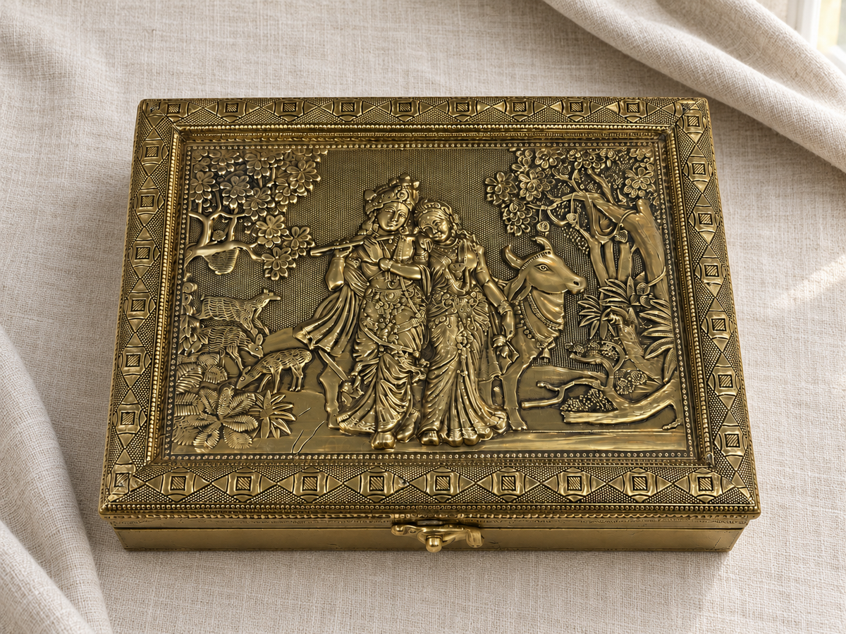 Gold-tone Radha Krishna jewellery box with decorative geometric borders on ivory linen